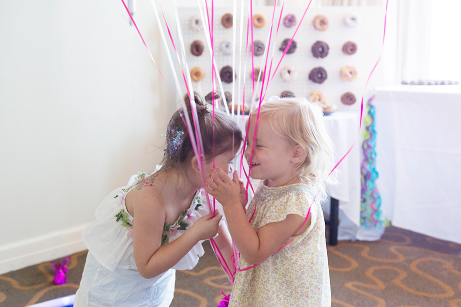Best friends in front of a donut wall.