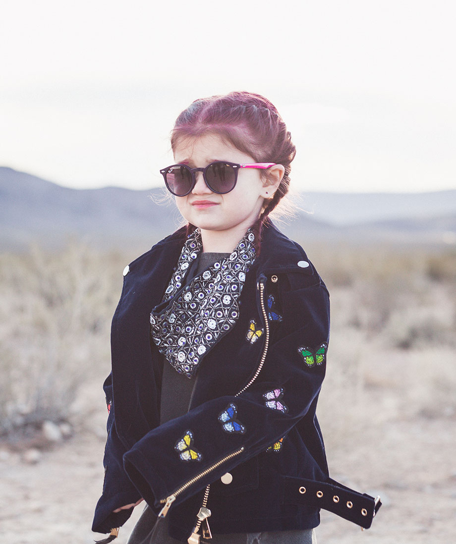 Zelda of Glitter and Bubbles stands in the desert of Las Vegas in a suede butterfly jacket.