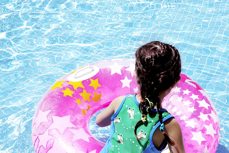 A little girl with braids in her hair sits in a pool float.