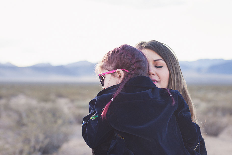 A mother and daughter hug while standing in the Las Vegas desert. 