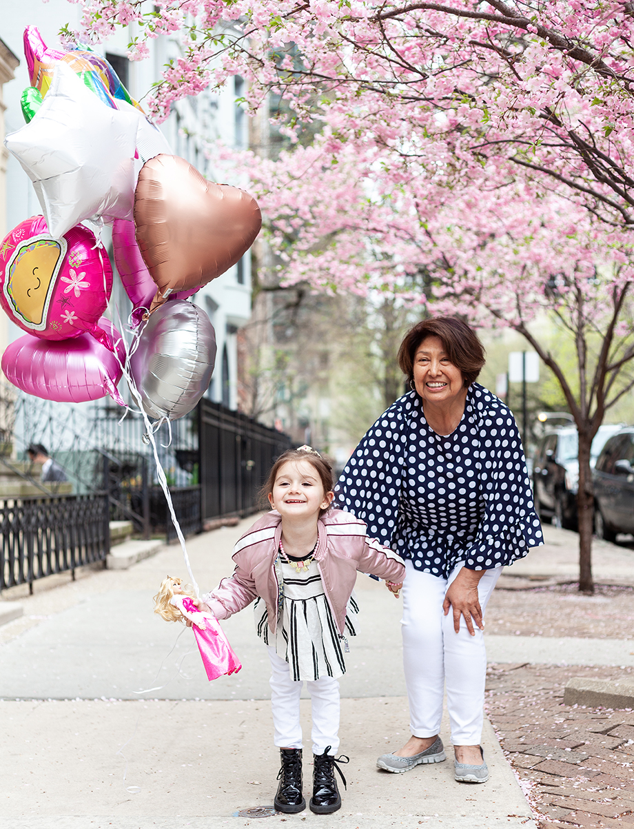 A little girl wearing pink holds a bundle of balloons outside in Chicago. 